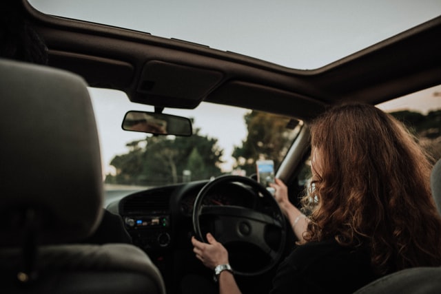 woman taking a picture on cell phone while driving before a car accident where the victim needs a Houston car accident attorney